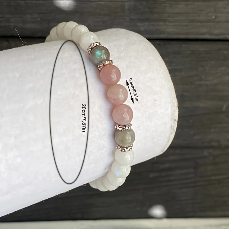 Hand wearing a spiritual healing bracelet made with moonstone, labradorite, and rose quartz