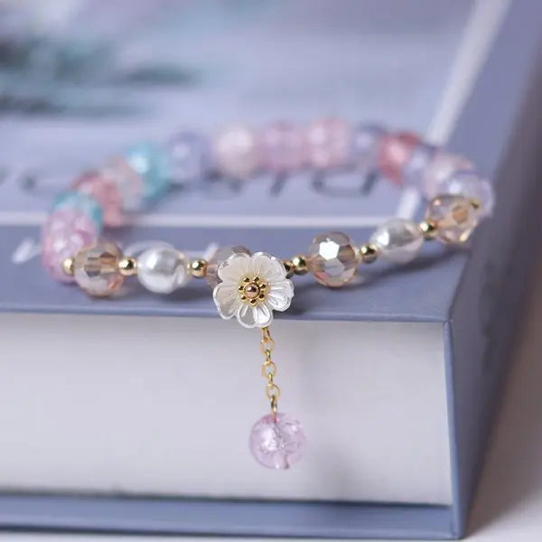 Pink and white flower tassel bracelet on model’s wrist